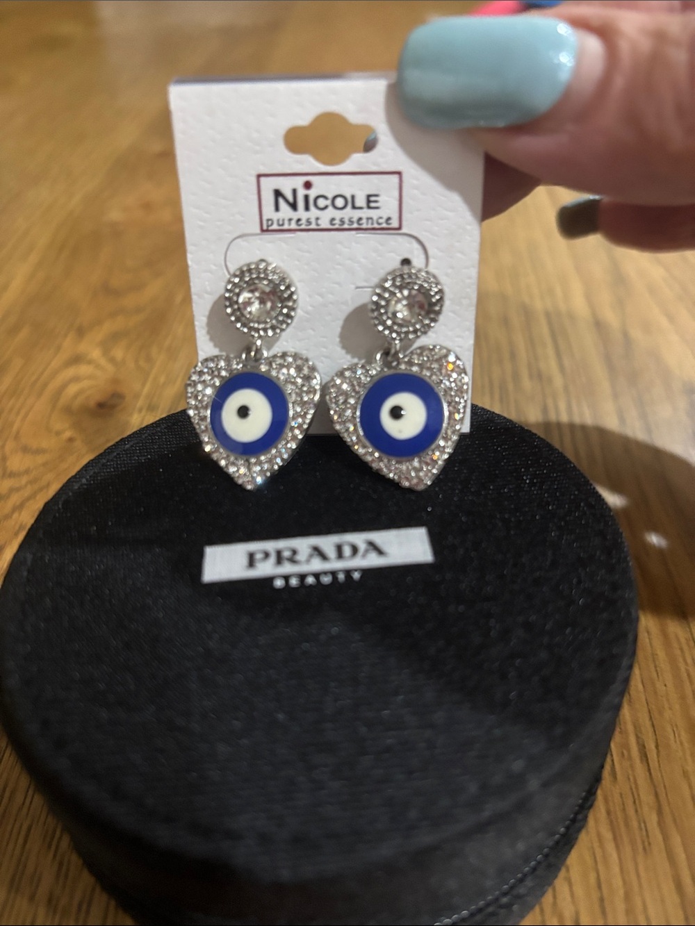 Nicole Heart Drop Earrings with Blue & White Evil Eye in a Prada beauty pouch